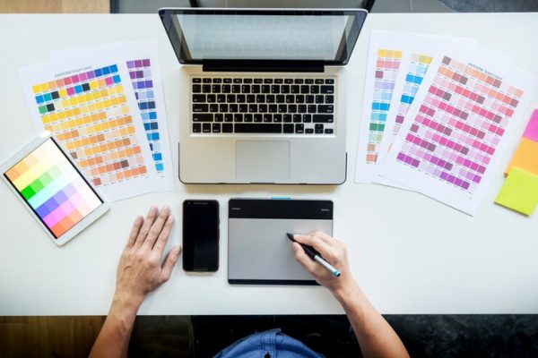 top-view-young-graphic-designer-working-desktop-computer-using-some-color-swatches-top-view_1423-139
